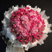 Bouquet of pink flowers with white ribbon held by a women