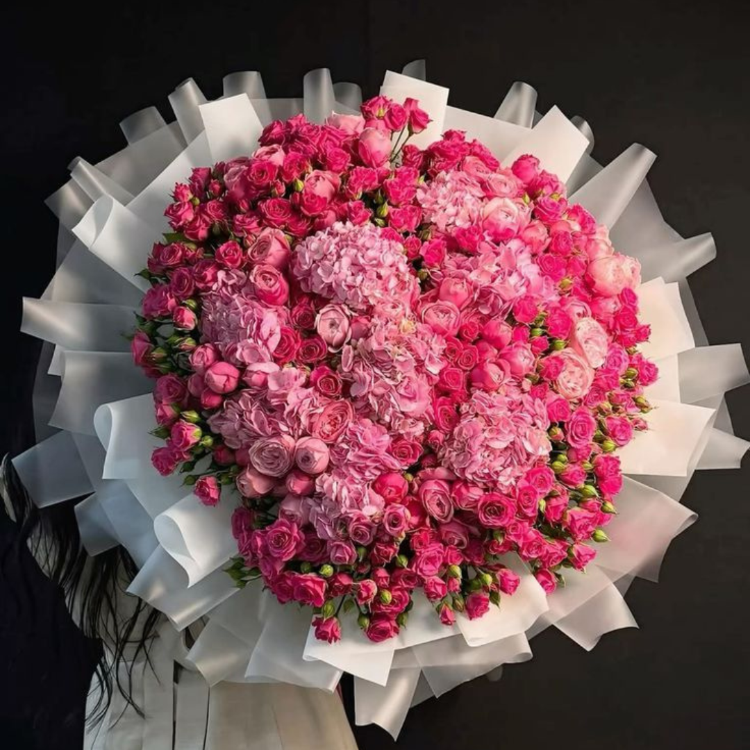 Bouquet of pink flowers with white ribbon held by a women