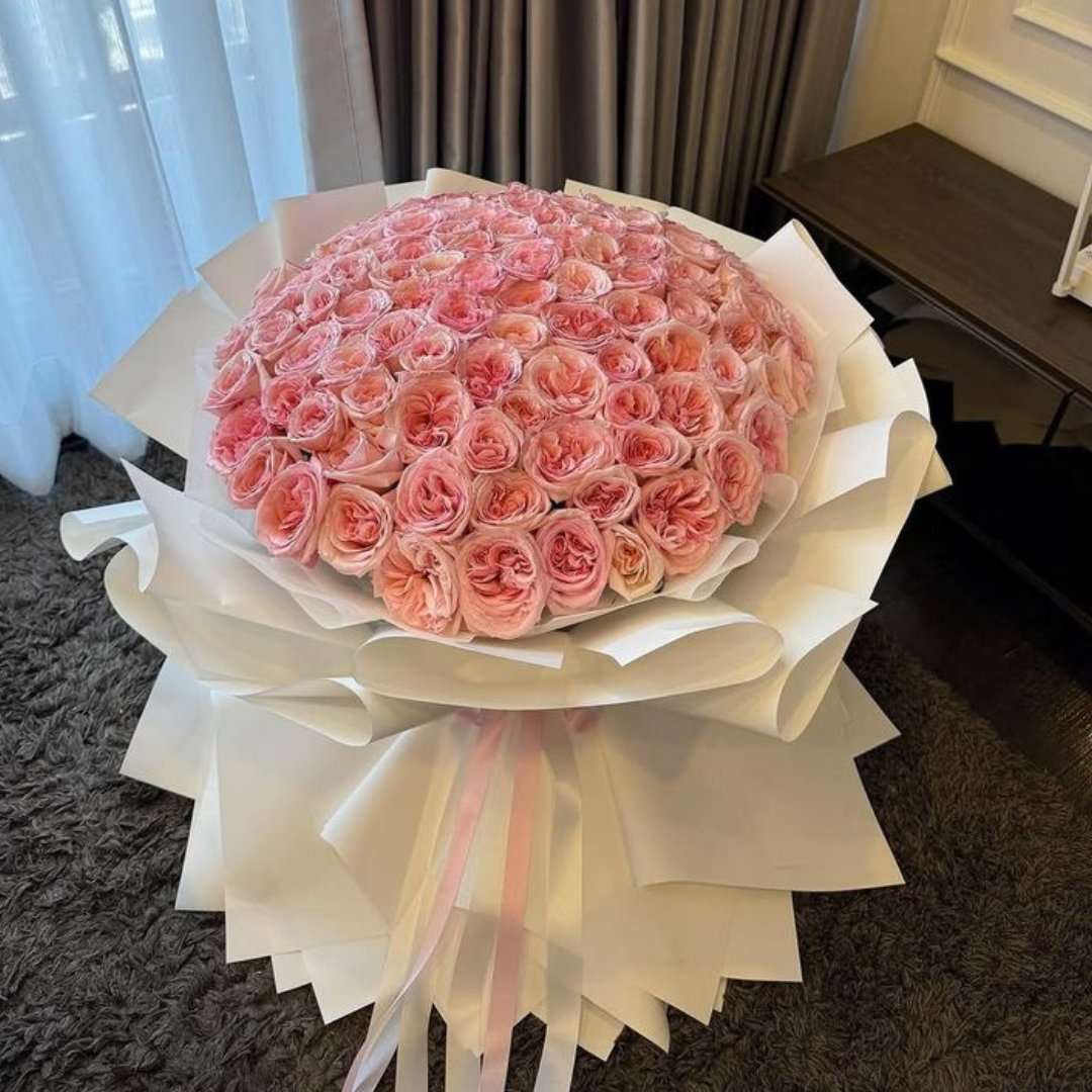 Bouquet of pink roses wrapped in white paper with a ribbon