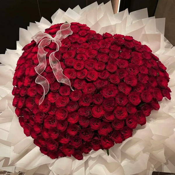 Heart-shaped arrangement of red roses with a white ribbon