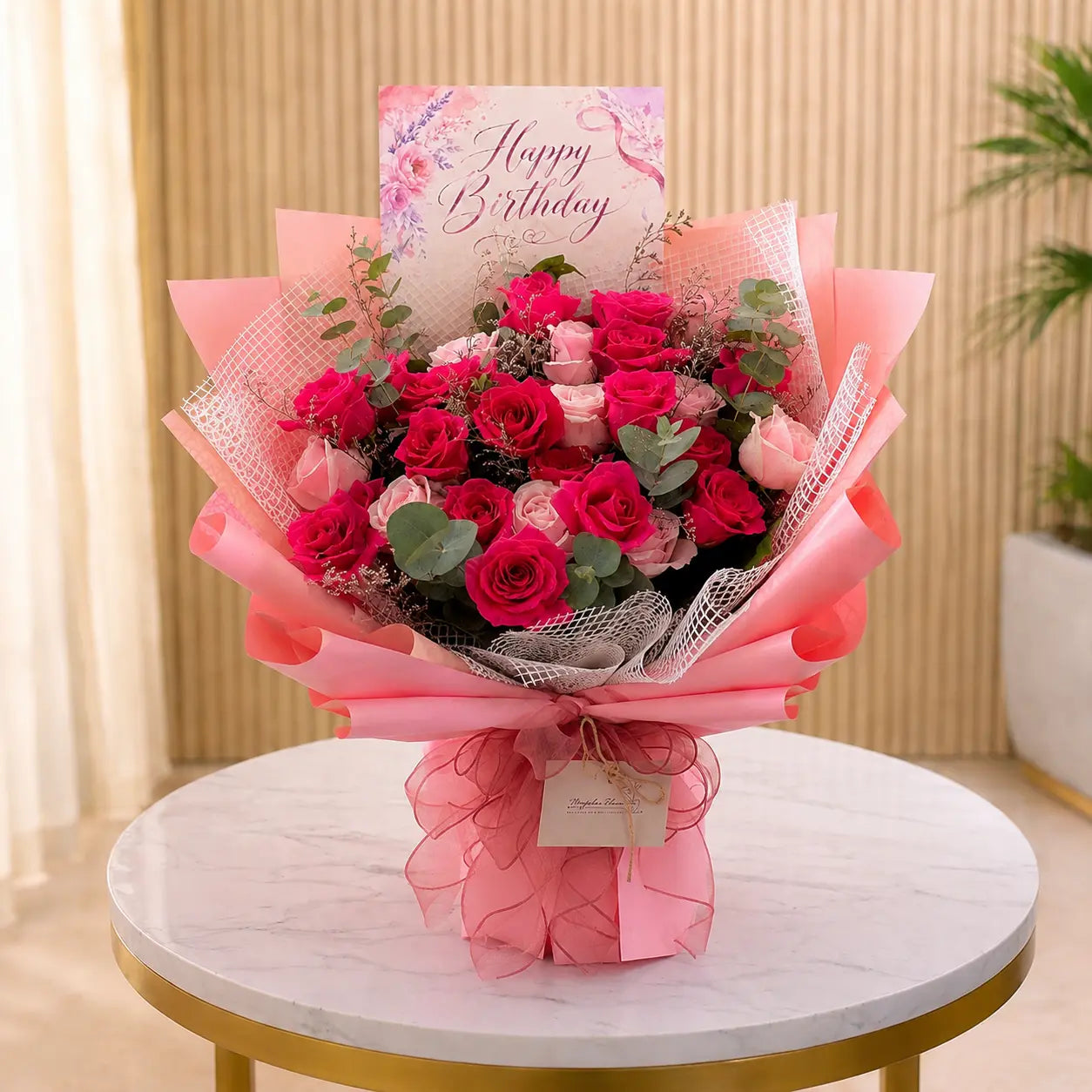 Bouquet of pink roses with a 'Happy Birthday' card on a marble table.