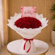 Bouquet of red roses with a birthday card on a round table.