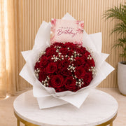 Happy birthday Bouquet of red roses with a 'Happy Birthday!' card on a marble table.